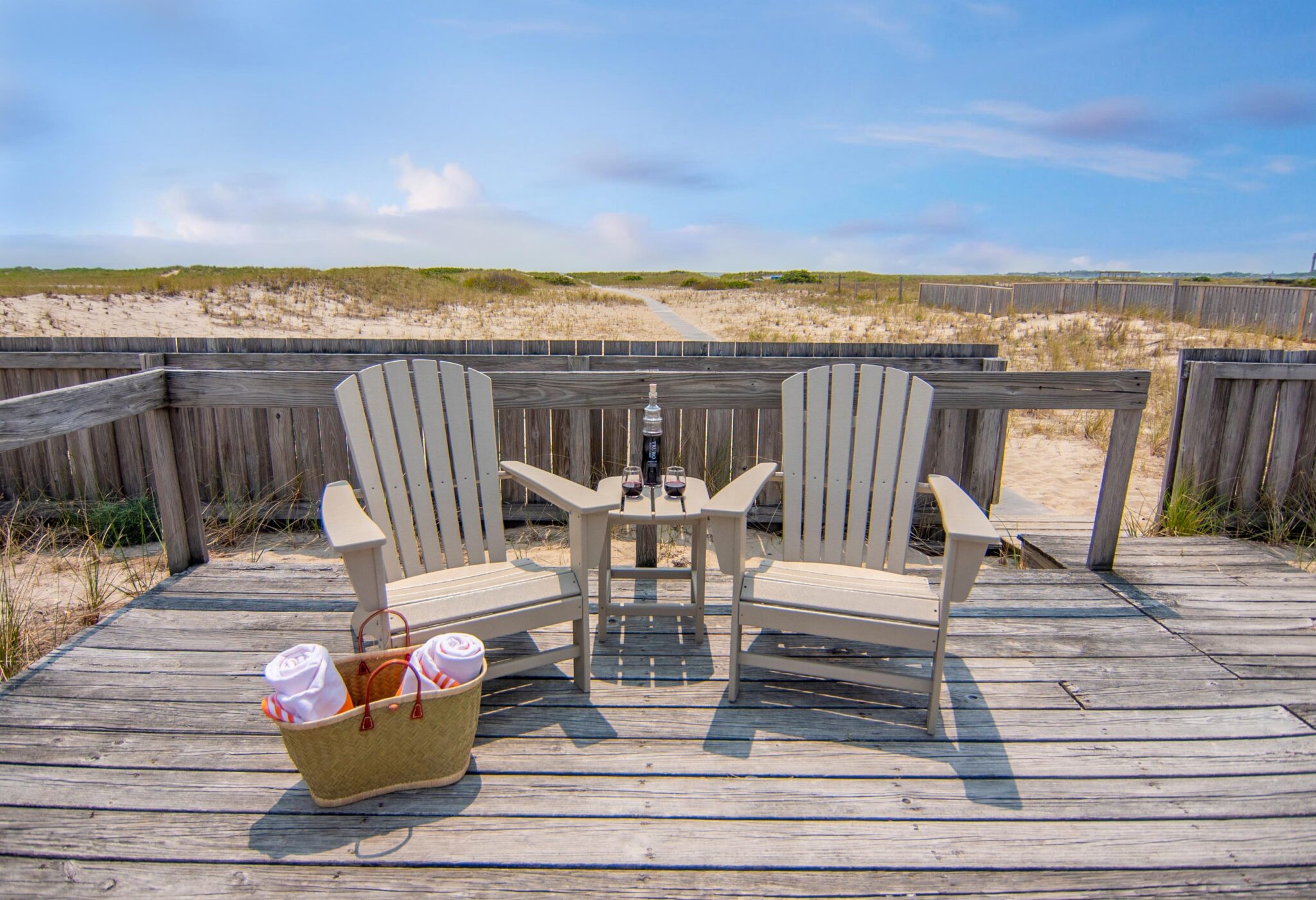 Two lounge chairs on a beach-front deck.