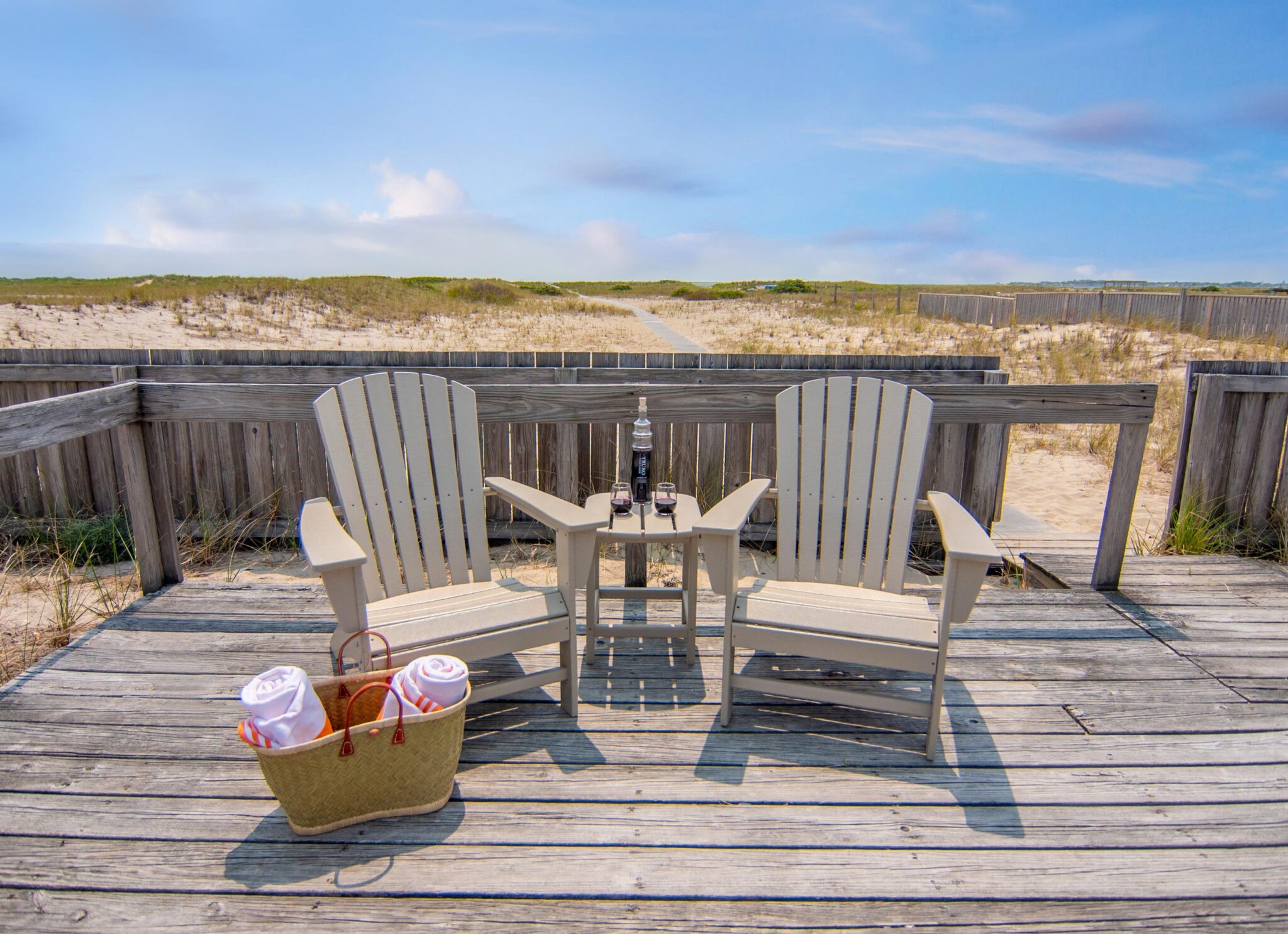 Two lounge chairs on a beach-front deck.